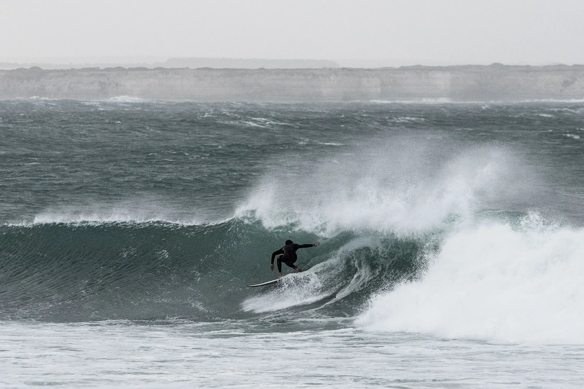 Surfista in azione su un’onda durante una mareggiata